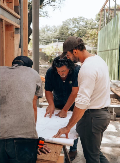 men standing at table looking at paper